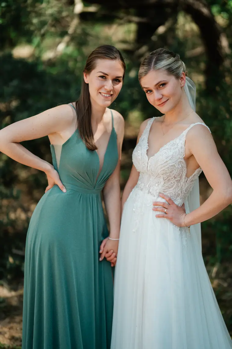 Braut und Trauzeugin im grünen Kleid posieren selbstbewusst im Wald