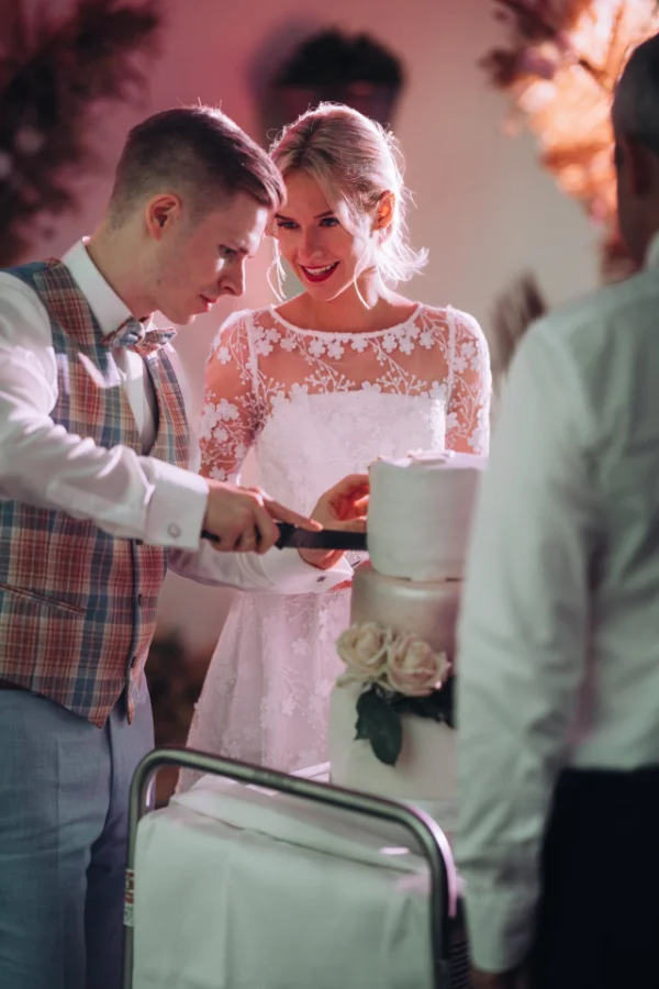 Das Brautpaar schneidet gemeinsam die Hochzeitstorte an